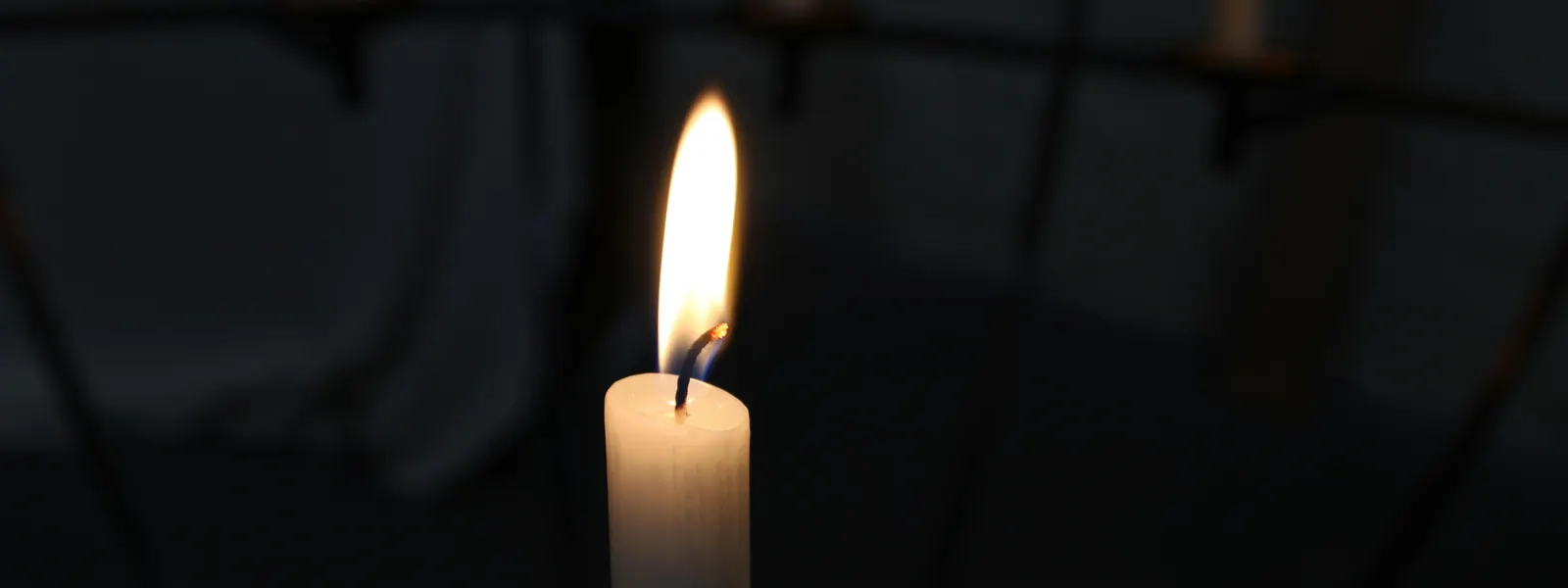A single candle flame burning in the dark